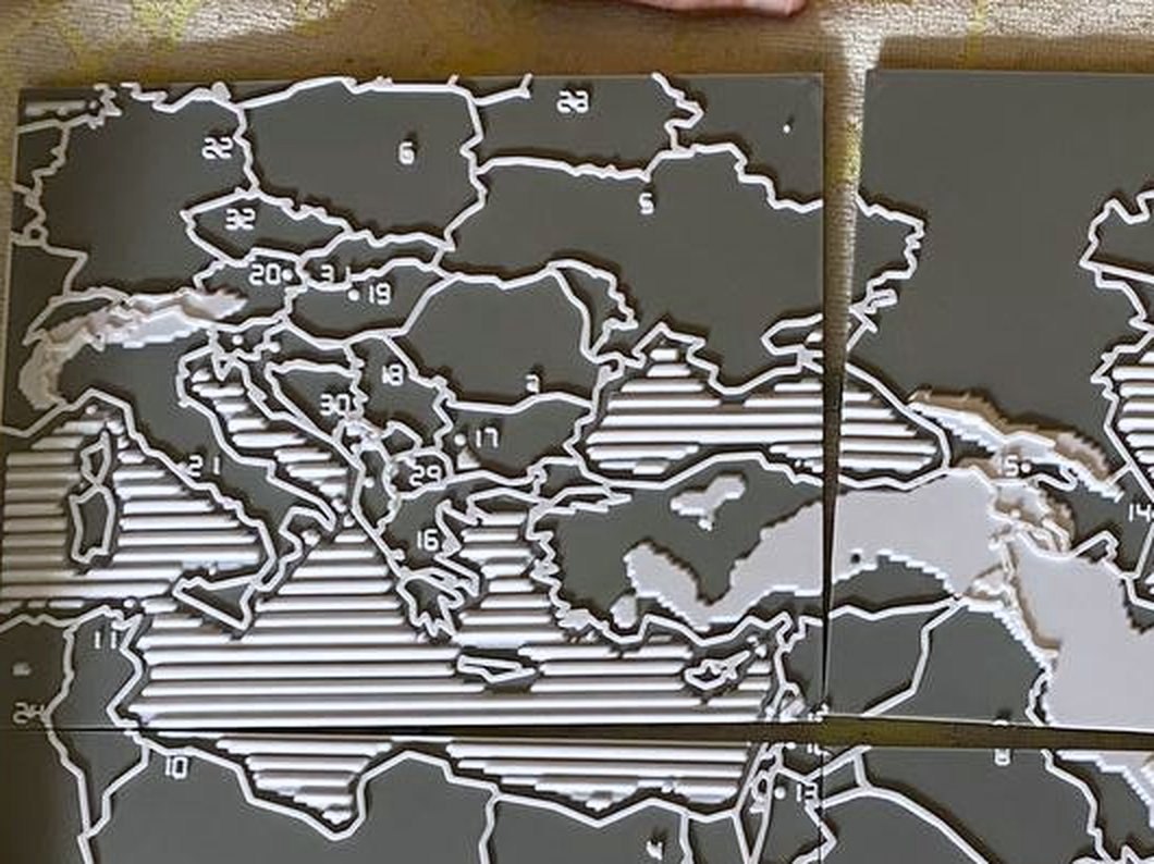 Fotografija prve odštampane karte izbliza: izdignute arapske cifre 20, 19, 18, 30 i 16 stoje unutar srednjoevropskih i balkanskih država, pored rebrastih mora i izdignutih belih granica.
